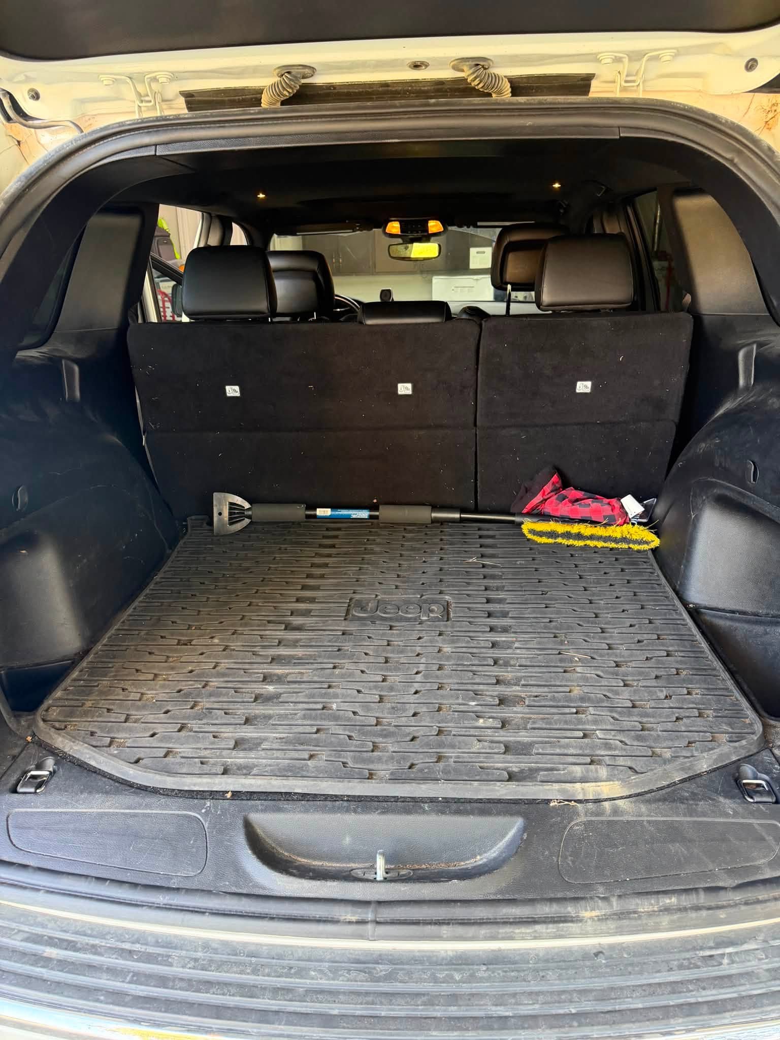 Jeep cargo area before detailing with debris and a dirty cargo liner